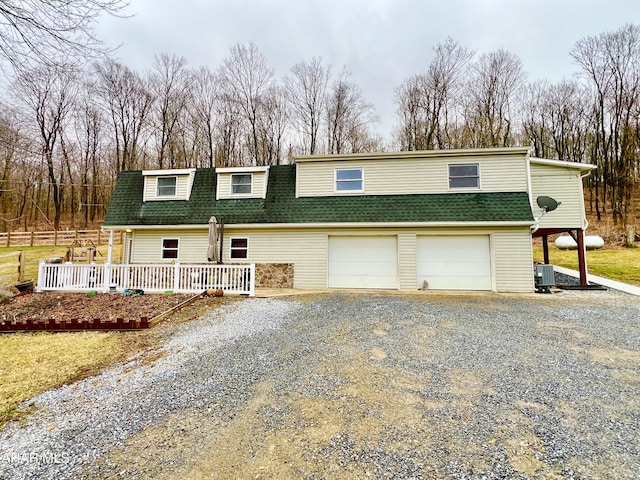 view of front facade featuring driveway, a garage, a shingled roof, fence, and central AC