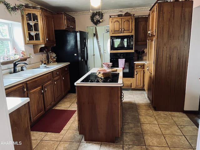 kitchen featuring black appliances, a center island, light tile patterned flooring, and sink