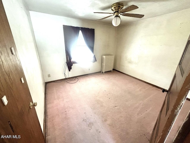 empty room with carpet flooring, ceiling fan, and radiator