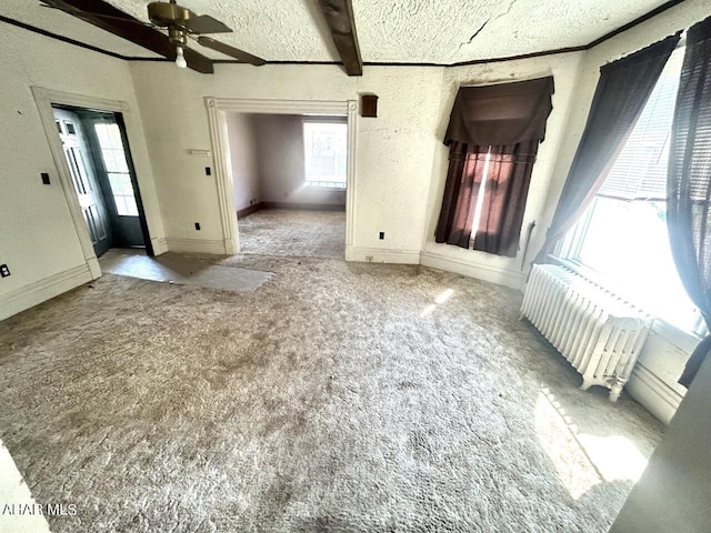 empty room with beam ceiling, a textured ceiling, light colored carpet, and radiator