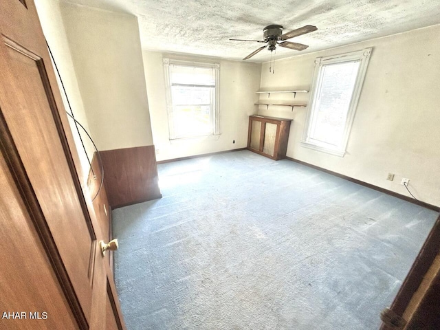 unfurnished living room with a textured ceiling, light colored carpet, and ceiling fan