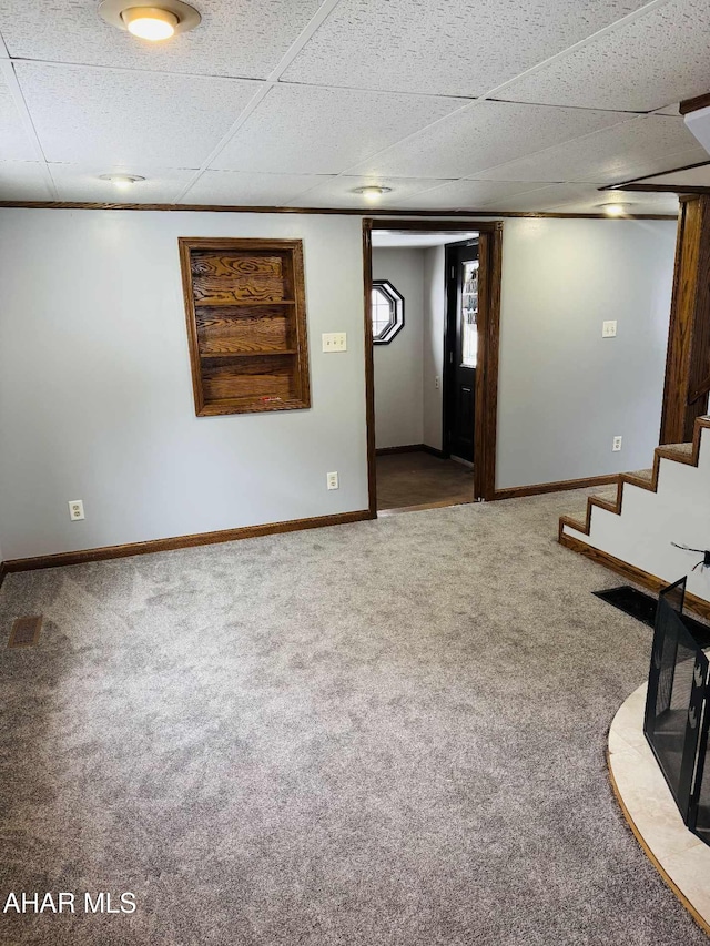 basement featuring crown molding, carpet floors, and a paneled ceiling