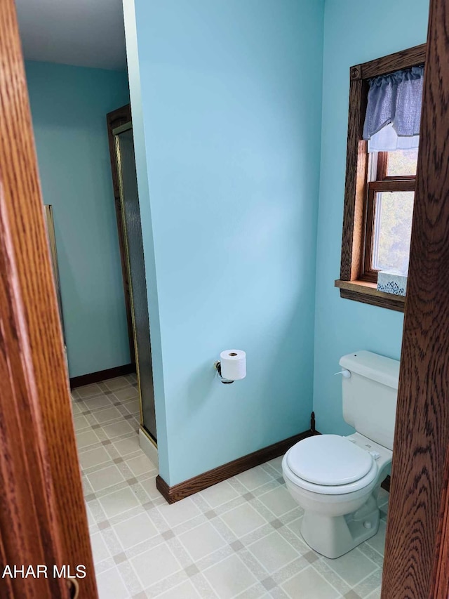 bathroom with a shower with shower door and toilet