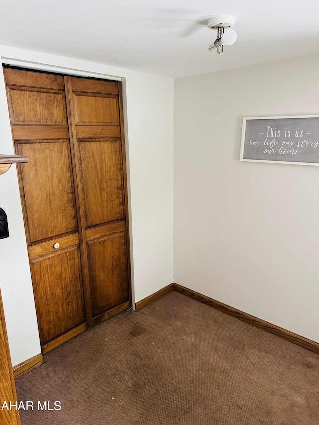 unfurnished bedroom featuring dark colored carpet and a closet