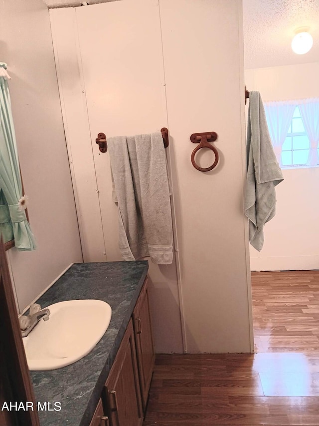 bathroom featuring vanity, wood-type flooring, and a textured ceiling