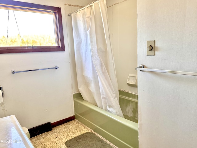 full bath featuring tile patterned floors, shower / tub combo with curtain, and baseboards