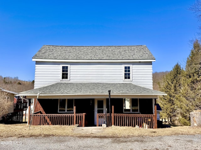 country-style home with roof with shingles and a porch