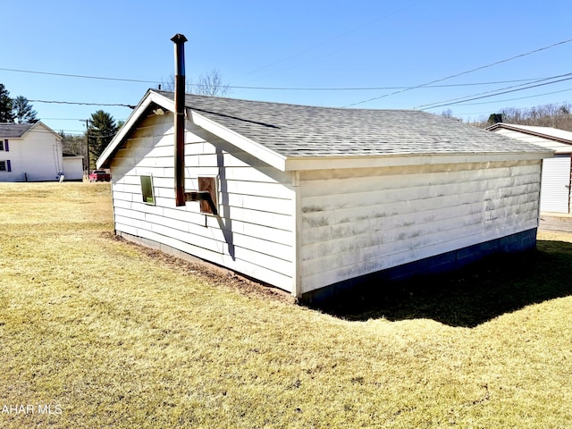 view of side of home featuring a lawn and a shingled roof