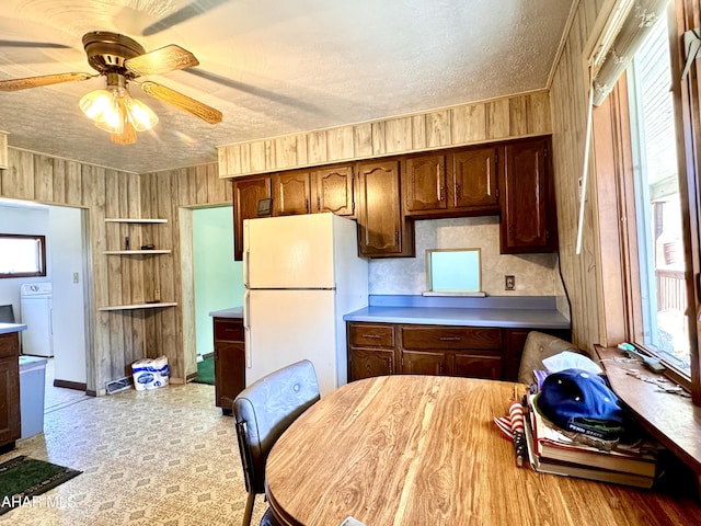 kitchen featuring a healthy amount of sunlight, a textured ceiling, freestanding refrigerator, and washer / clothes dryer