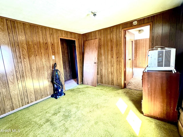 carpeted empty room featuring wood walls and baseboards