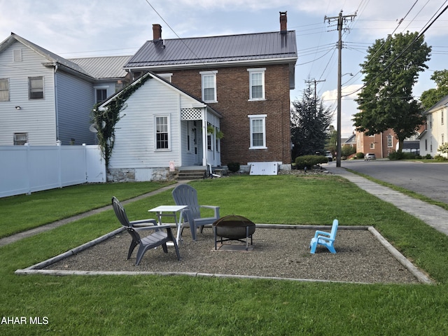 back of house with a yard and an outdoor fire pit