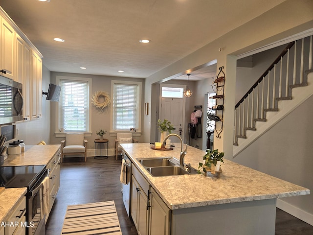 kitchen featuring a kitchen island with sink, sink, dark hardwood / wood-style floors, light stone counters, and stainless steel appliances