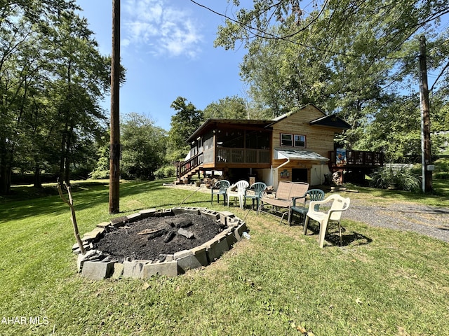 view of yard with a fire pit, a deck, and a sunroom