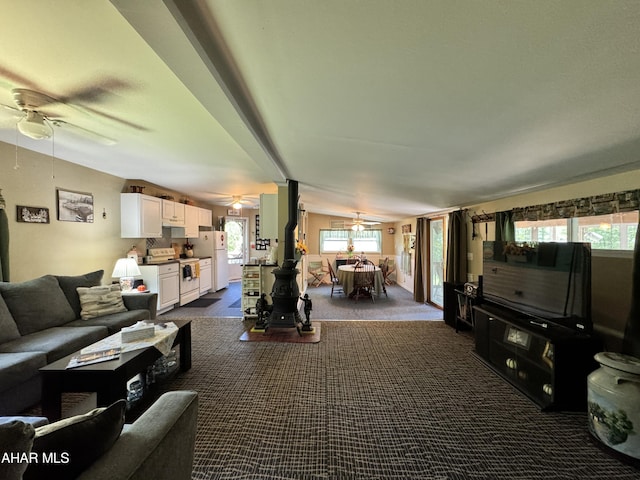 carpeted living room with a wood stove, plenty of natural light, and lofted ceiling