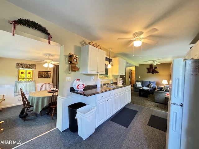 kitchen with white refrigerator, white cabinetry, sink, and dark carpet