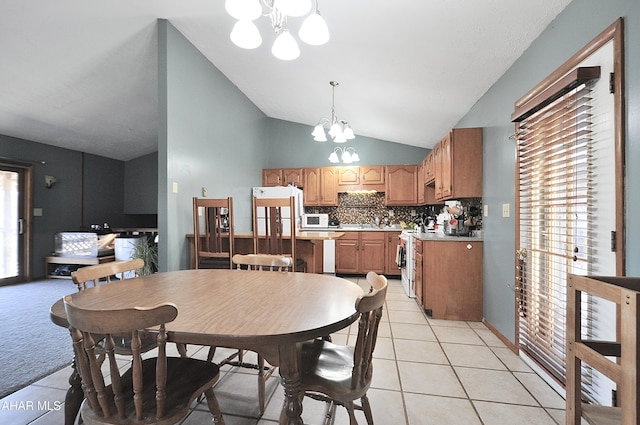 dining room featuring light tile patterned flooring, a notable chandelier, a wealth of natural light, and vaulted ceiling