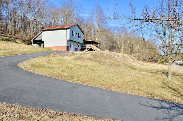 view of property exterior with aphalt driveway, stairway, and a lawn