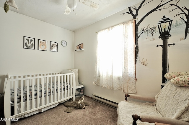 bedroom with a crib, a baseboard heating unit, carpet floors, and ceiling fan