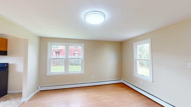 interior space featuring light wood-style flooring, plenty of natural light, and a baseboard heating unit