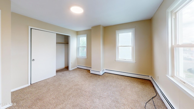 unfurnished bedroom with carpet floors, a baseboard radiator, a closet, and baseboards