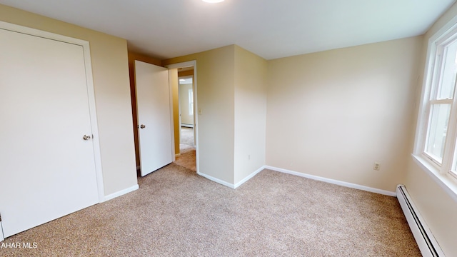 unfurnished bedroom with a baseboard radiator, baseboards, and carpet floors