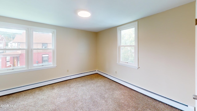 carpeted empty room with a baseboard heating unit