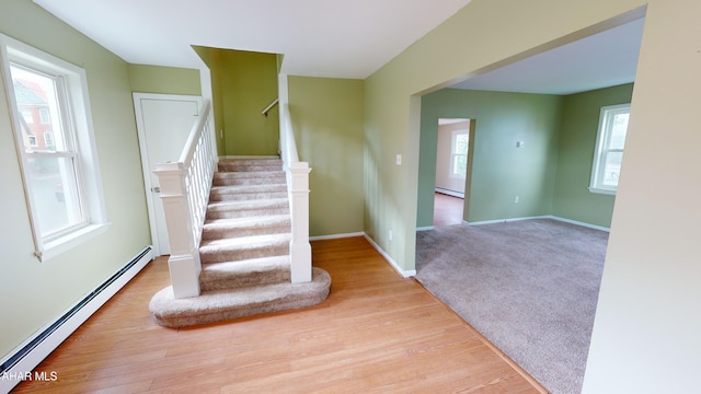 stairway featuring a baseboard radiator, baseboards, and wood finished floors