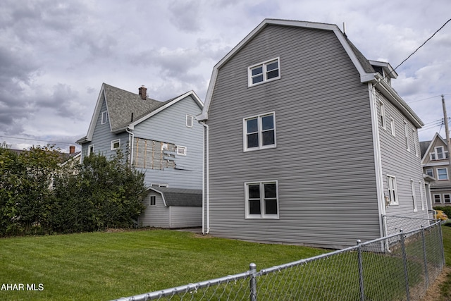 rear view of house with fence private yard, a gambrel roof, and a lawn