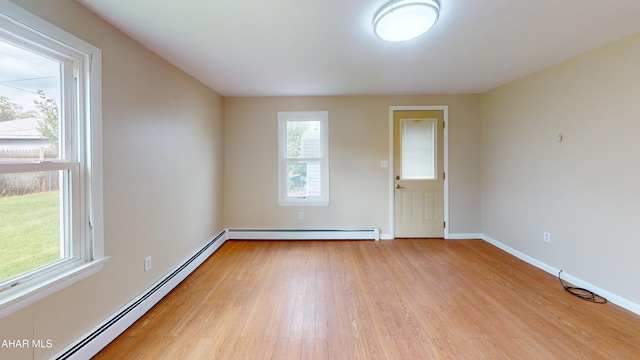 unfurnished room featuring light wood-style floors, a baseboard heating unit, and baseboards