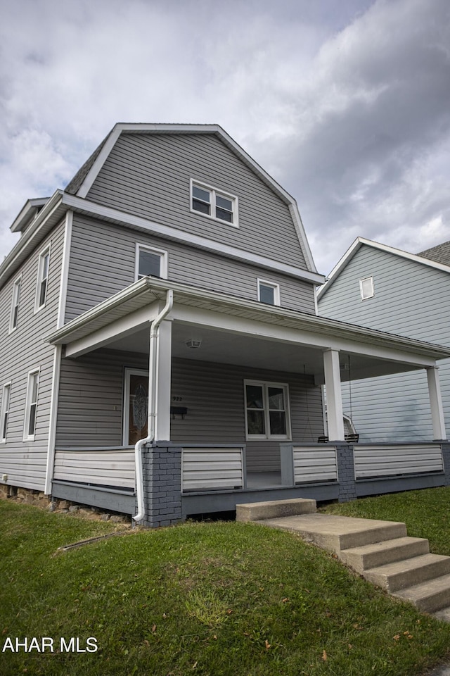view of front facade featuring a gambrel roof, covered porch, and a front yard
