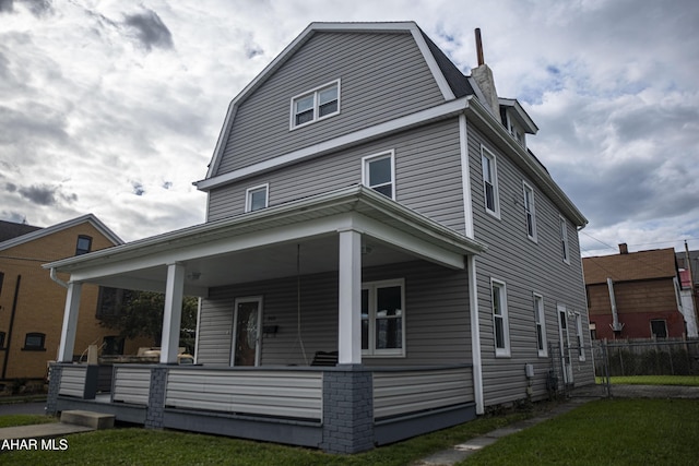 back of property featuring a yard, a porch, a gambrel roof, and fence