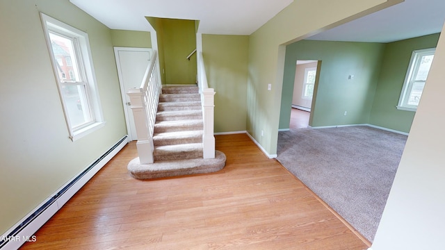 stairway with baseboard heating, baseboards, and wood finished floors