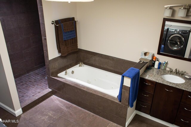 bathroom with plus walk in shower, vanity, washer / clothes dryer, and tile patterned flooring