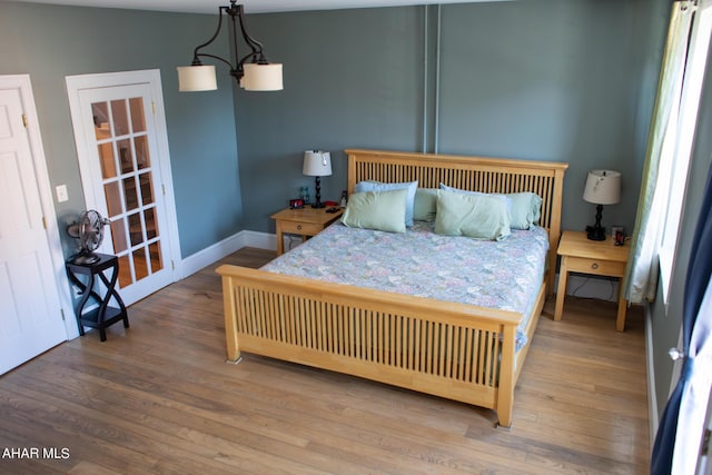 bedroom with hardwood / wood-style flooring and an inviting chandelier