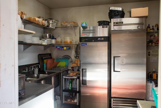 kitchen featuring stainless steel fridge with ice dispenser, sink, and stainless steel refrigerator