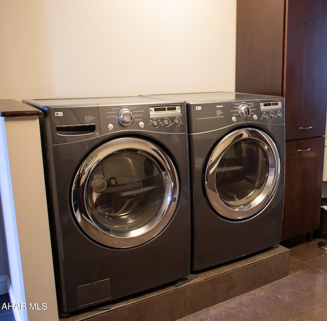 laundry area with dark tile patterned floors and separate washer and dryer