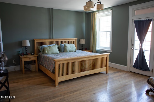 bedroom featuring hardwood / wood-style flooring, a chandelier, and multiple windows