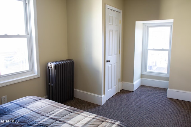 unfurnished bedroom featuring dark carpet and radiator