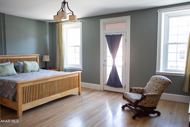 bedroom with multiple windows, wood-type flooring, and an inviting chandelier