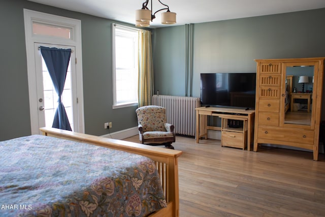 bedroom featuring hardwood / wood-style floors, an inviting chandelier, and radiator