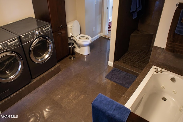 laundry area with dark tile patterned floors and washer and clothes dryer