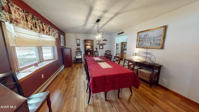 dining space featuring hardwood / wood-style flooring, a baseboard radiator, and a textured ceiling