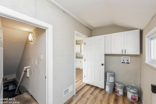 laundry room with washer hookup, light hardwood / wood-style floors, and cabinets