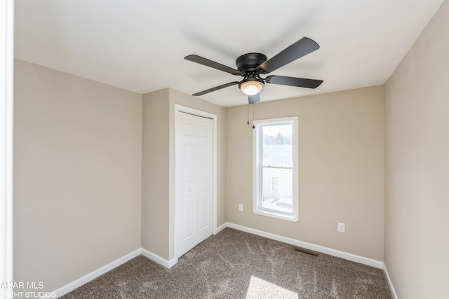 unfurnished bedroom with ceiling fan, a closet, and carpet