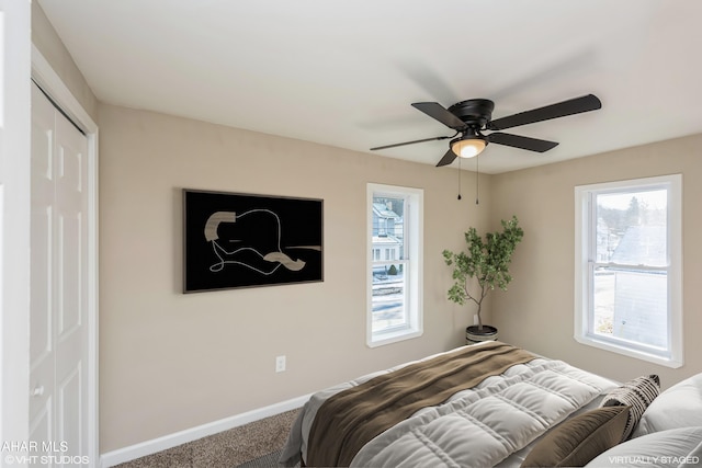 carpeted bedroom with ceiling fan and a closet