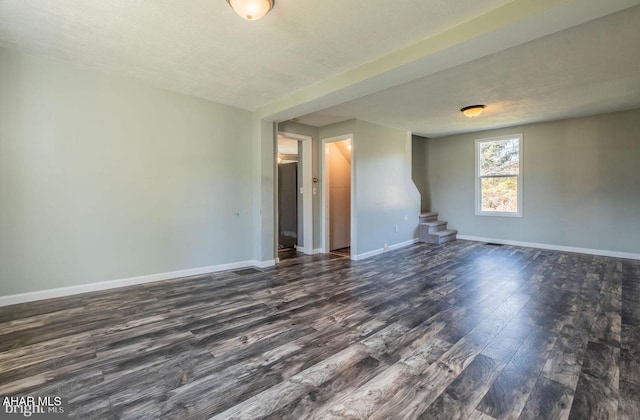 spare room featuring stairs, dark wood finished floors, and baseboards