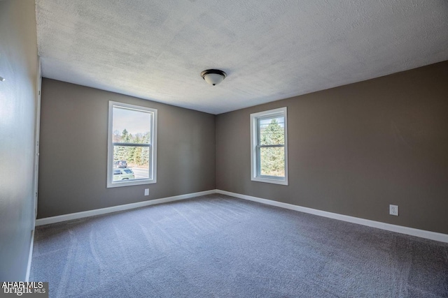 unfurnished room featuring a healthy amount of sunlight, baseboards, carpet floors, and a textured ceiling