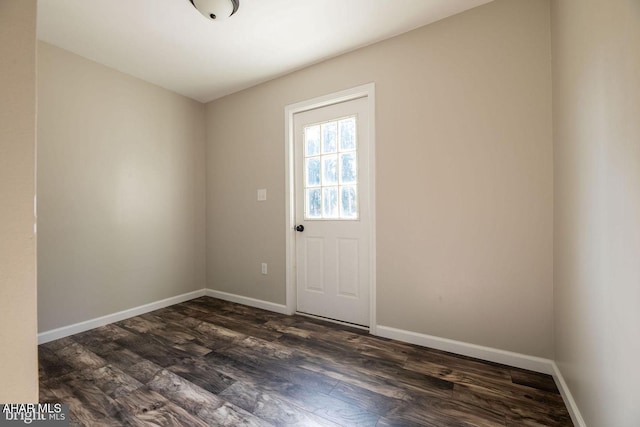 doorway with dark wood-type flooring and baseboards