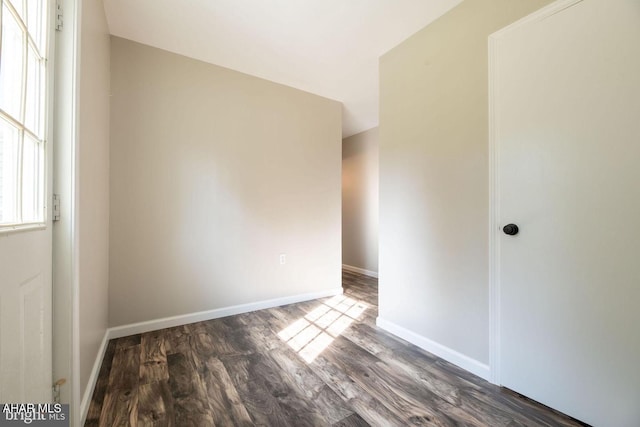 spare room with baseboards and wood finished floors