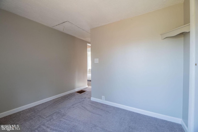 empty room with visible vents, a textured ceiling, baseboards, and carpet floors